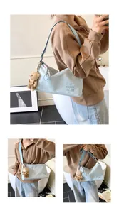 Détail du sac messager bleu clair avec lettrage CHUU DON et un charmant ours en peluche