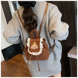 Détail d'un mini sac à dos en velours marron à pois avec bordure en dentelle blanche