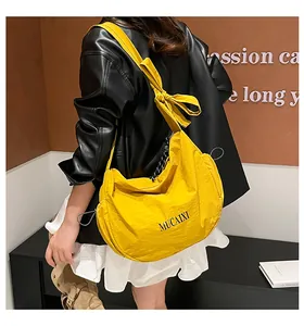 Detail of a bright yellow crescent nylon bag with side drawstrings and bow strap detail