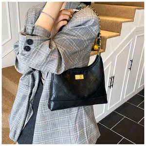 Détail du sac à bandoulière en cuir matelassé noir avec chaîne dorée et fermoir rotatif