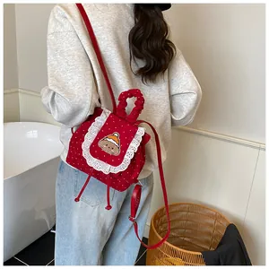 Détail du sac à dos rouge à pois avec bordure en dentelle et broderie ours