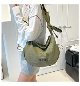 Detail of avocado green crescent nylon crossbody bag with adjustable knot straps and drawstring