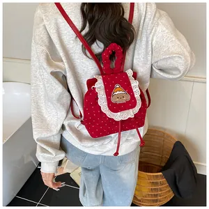 Détail d'un sac à dos en velours côtelé à pois rouges avec dentelle et broderie