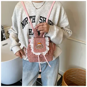 Détail d'un mini sac à dos en velours rose avec broderie chien et dentelle