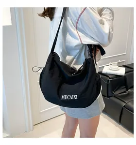 Detail view of black nylon crescent bag featuring side drawstring and white logo print