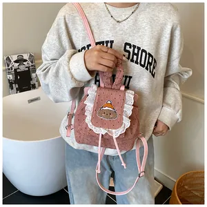 Détail d'un mini sac à dos en velours côtelé rose avec dentelle et broderie chiot