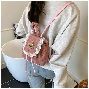 Détail du mini sac à dos en velours côtelé rose avec dentelle et écusson ours en peluche