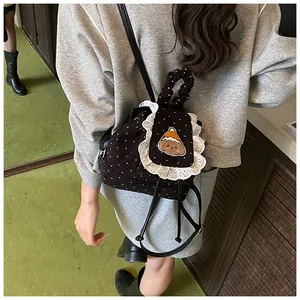 Détail d'un sac à dos en velours côtelé noir avec bordure dentelle et écusson ours brodé
