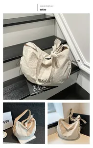 Detail view of white nylon crescent bag with bow-knot shoulder straps and side drawstring