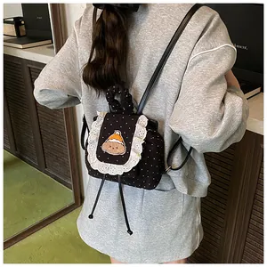 Détail de broderie d'ours et bordure en dentelle sur sac à dos en velours à pois