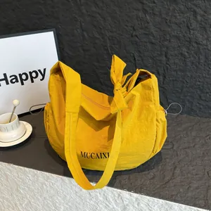 Bright yellow nylon hobo bag with pleated texture and decorative ribbon straps