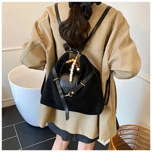 Detail eines schwarzen Multifunktionsrucksacks mit Perlenanhänger und Goldbeschlägen