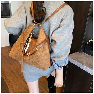 Detailansicht des braunen Vintage-Rucksacks mit matter Textur und dekorativem Perlenanhänger