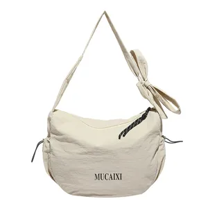 Beige nylon crescent hobo bag with large bow shoulder strap and brand logo