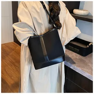 Model view of black matte and glossy leather bucket bag with adjustable shoulder strap
