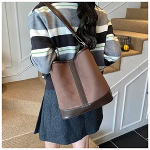 Detail of dark brown matte and smooth leather bucket bag styled with casual outfit