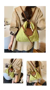 Detailaufnahme des grünen Wildleder-Rucksacks mit Lederriemen und Perlenanhänger