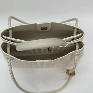 Cream white woven tote bag featuring dual compartments and elegant gold hardware