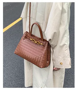 Detailed view of brown woven leather texture and gold knot buckle on crossbody bag