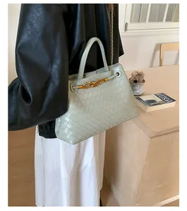 Detailed close-up of light green woven leather texture and elegant gold knot buckle