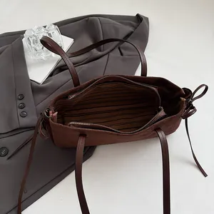 Deep brown suede baguette shoulder bag with striped interior and bow detail on the side