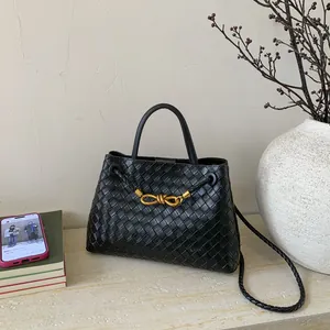 Close-up of black woven leather texture with gold metal knot buckle on a bucket bag