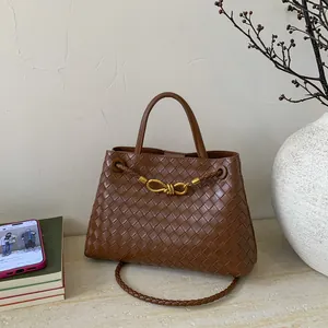 Detail of brown woven leather texture and golden knot hardware on a bucket bag