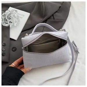 Close-up of light purple crocodile embossed handbag with grey herringbone lining and zipper pocket