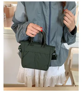 Detail einer dunkelgrünen Nylontasche mit gepolstertem Griff und schwarzem Schultergurt