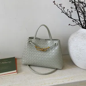 Detail of light green woven leather bucket bag with signature gold knot hardware