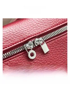 Détail du double zip en métal argenté sur un sac en cuir grainé rouge élégant