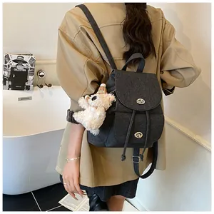 Nahaufnahme von grauem Retro-Rucksack mit Metalldrehverschluss und süßem Plüschbär