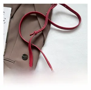 Détail d'un sac à main rouge en cuir litchi avec fermeture éclair argentée et bandoulière