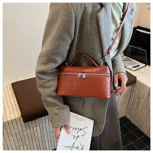 Detail of red croc-embossed leather box bag with silver zippers and top handle