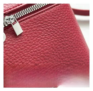 Détail de la texture cuir grainé rouge et de la fermeture éclair en métal argenté du sac