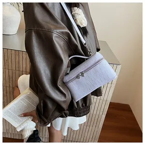 Close-up of a lilac crocodile pattern lunchbox bag styled with a brown leather jacket