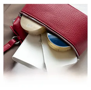 Détail du sac rouge en cuir grainé montrant l'intérieur spacieux et la fermeture