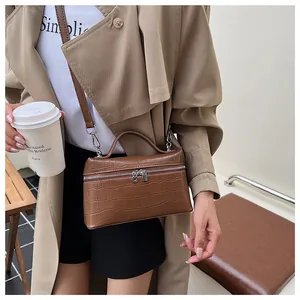 Detail of brown crocodile pattern handbag with dual zippers and silver metal hardware