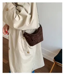 Close-up of brown suede underarm bag with silver chain strap and zipper detail