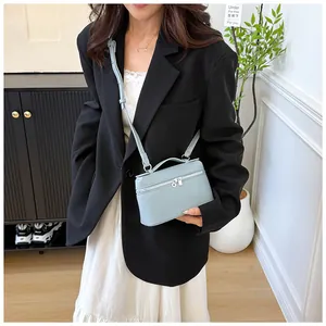 Détail d'un mini sac carré en cuir grainé bleu clair avec bandoulière et finitions argentées
