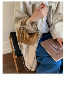 Brown suede underarm bag detail featuring silver chain strap and leather fringe tassel
