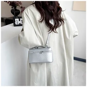 Mini sac carré argenté en cuir grainé porté avec un trench-coat beige élégant et moderne