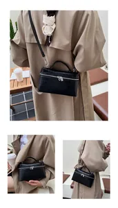 Detail of black crocodile texture handbag with silver zipper and top handle view