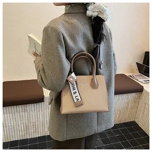 Detail of light brown woven handbag with leather trim and fashion strap on blazer