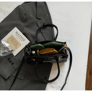 Top view of open black tote bag showing daily essentials like phone case and wallet