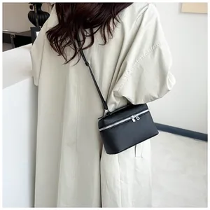 Détail d'un mini sac en cuir noir grainé avec fermeture éclair argentée sur un modèle