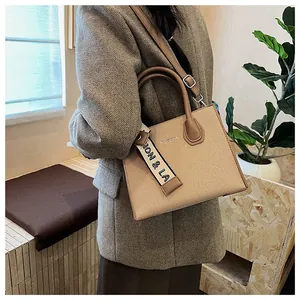 Detail of beige canvas square bag with faux leather trim and decorative silk scarf