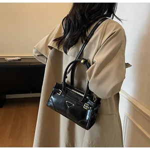 Polished black leather handbag featuring metal triangle logo and adjustable side straps