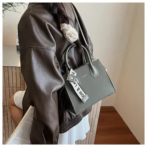 Detailed side view of dark green textured leather handbag with fashion ribbon decor