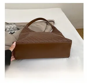 Detail of dark brown woven tote bag showing durable leather bottom and textured weave